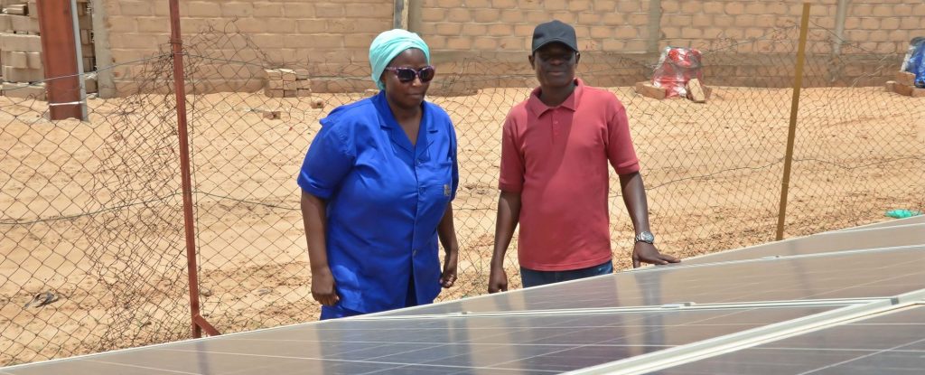 A woman and a man are inspecting solar panels in front of a house