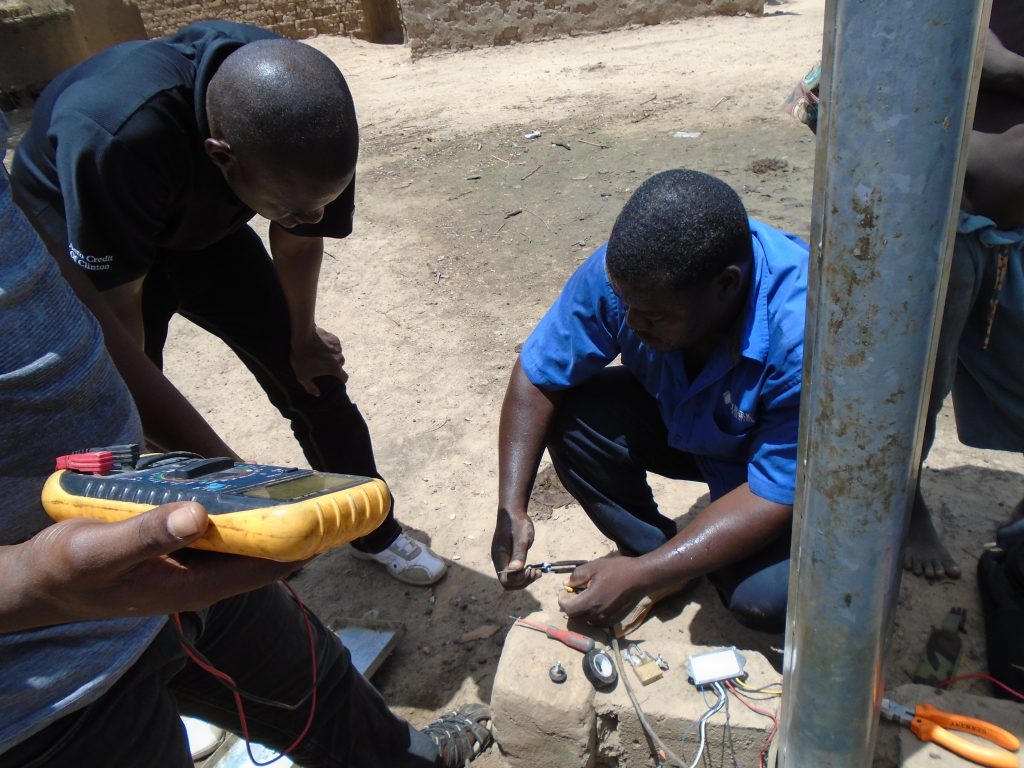 Three Malian technicians are conducting a streetlight maintenance.